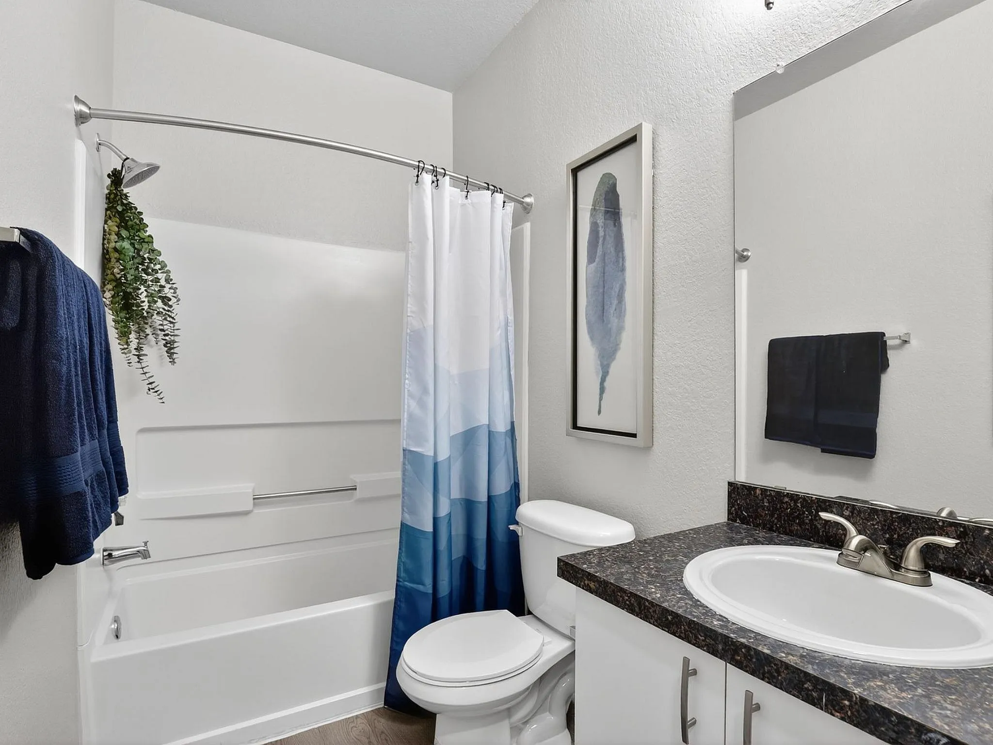 Modern bathroom with elegant design featuring a sleek countertop, stylish sink, and soothing blue shower curtain.