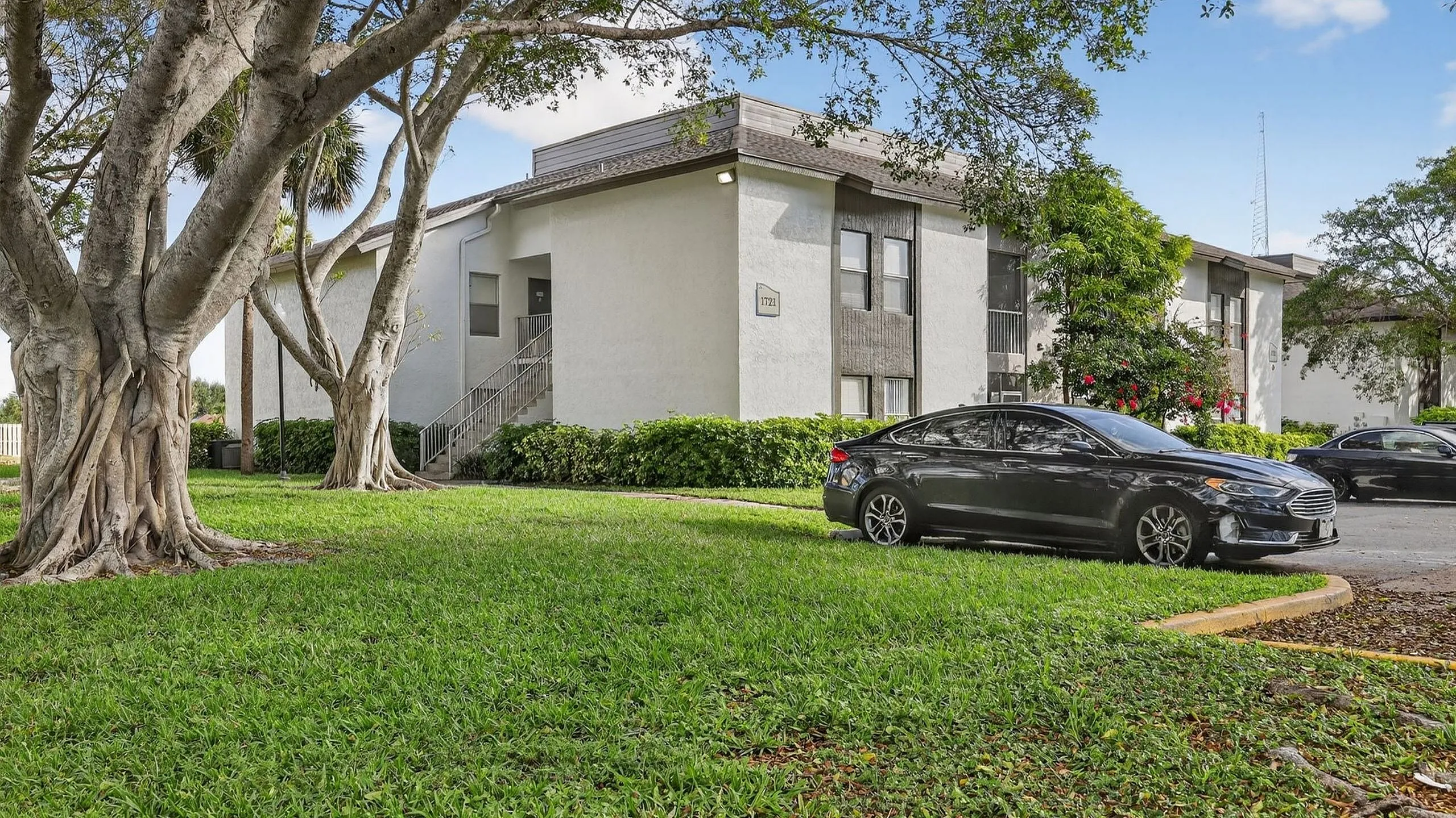 Charming apartment building surrounded by lush greenery and mature trees, exuding a serene and welcoming ambiance.