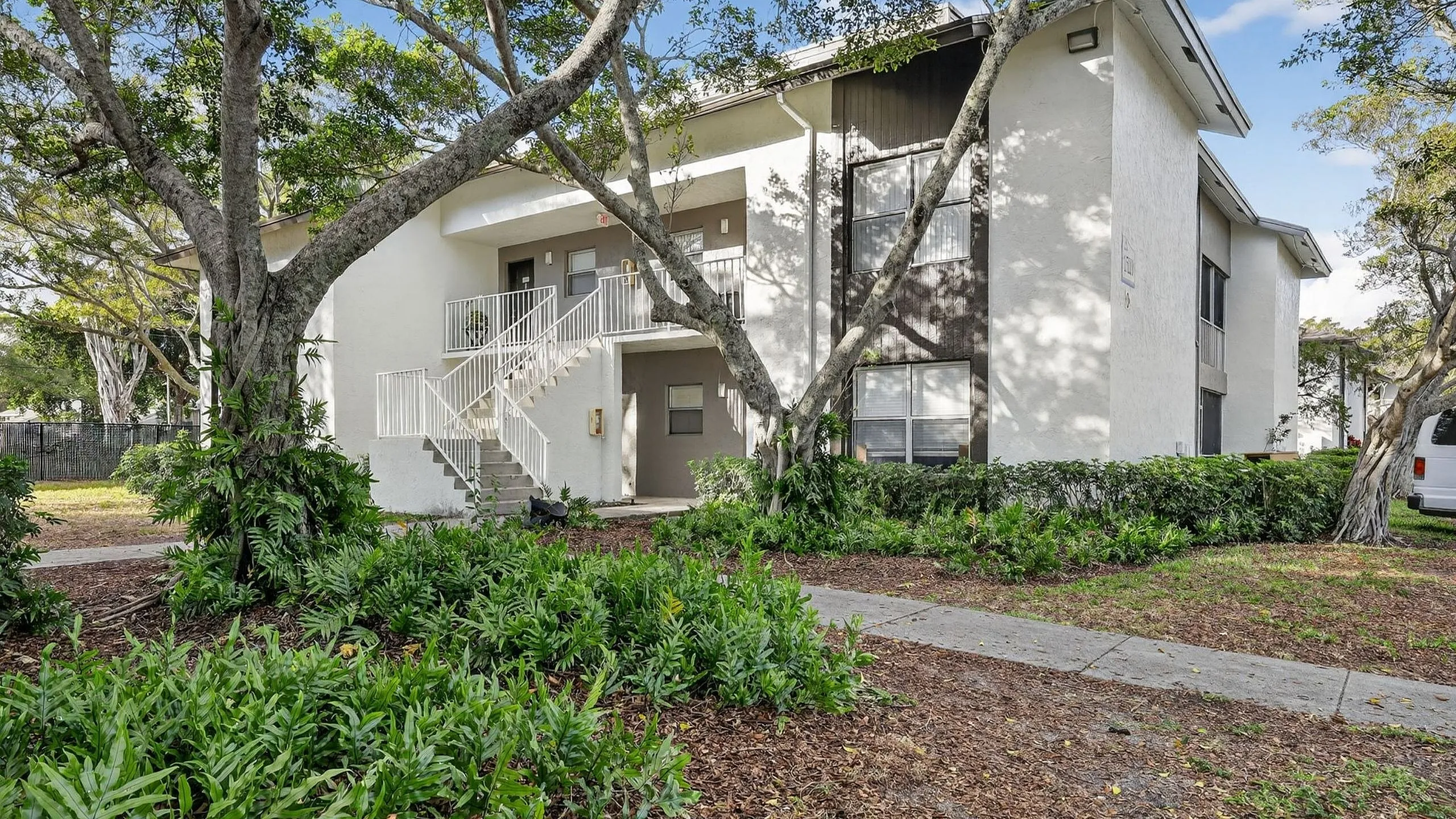 Charming apartment building surrounded by lush greenery and trees, offering a peaceful and inviting atmosphere.