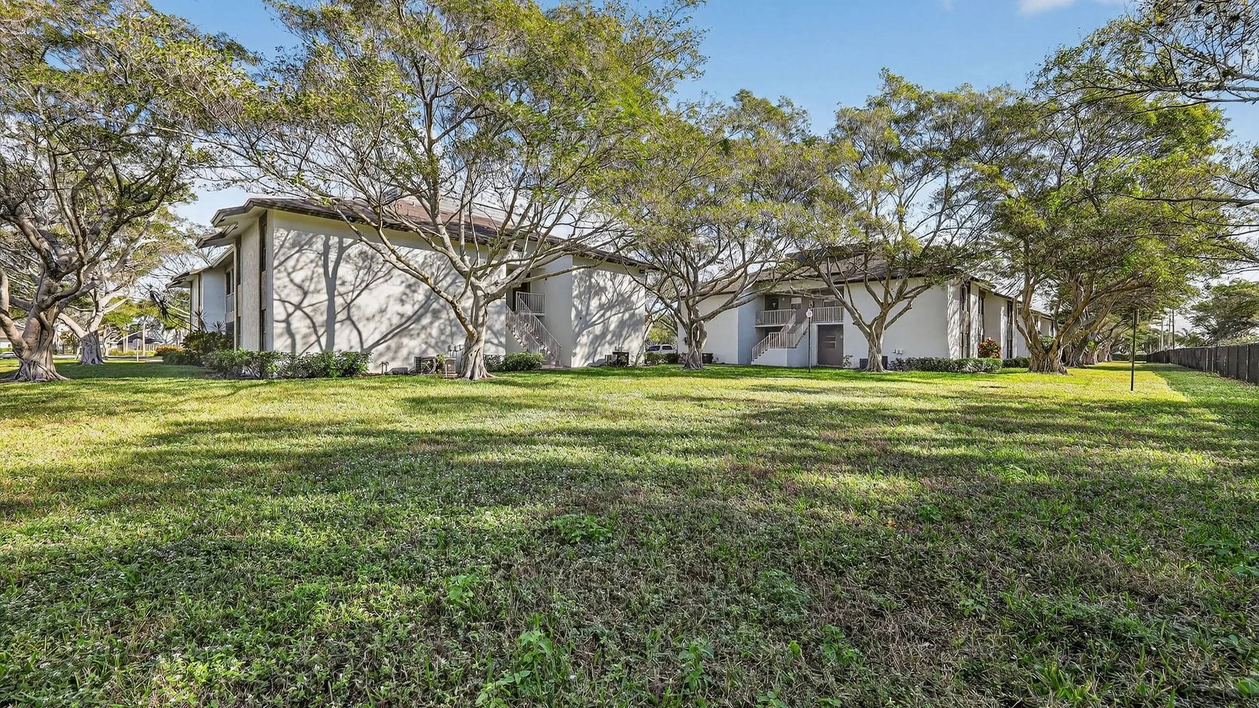 Beautiful apartment complex surrounded by lush greenery and mature trees, offering a tranquil and inviting atmosphere.