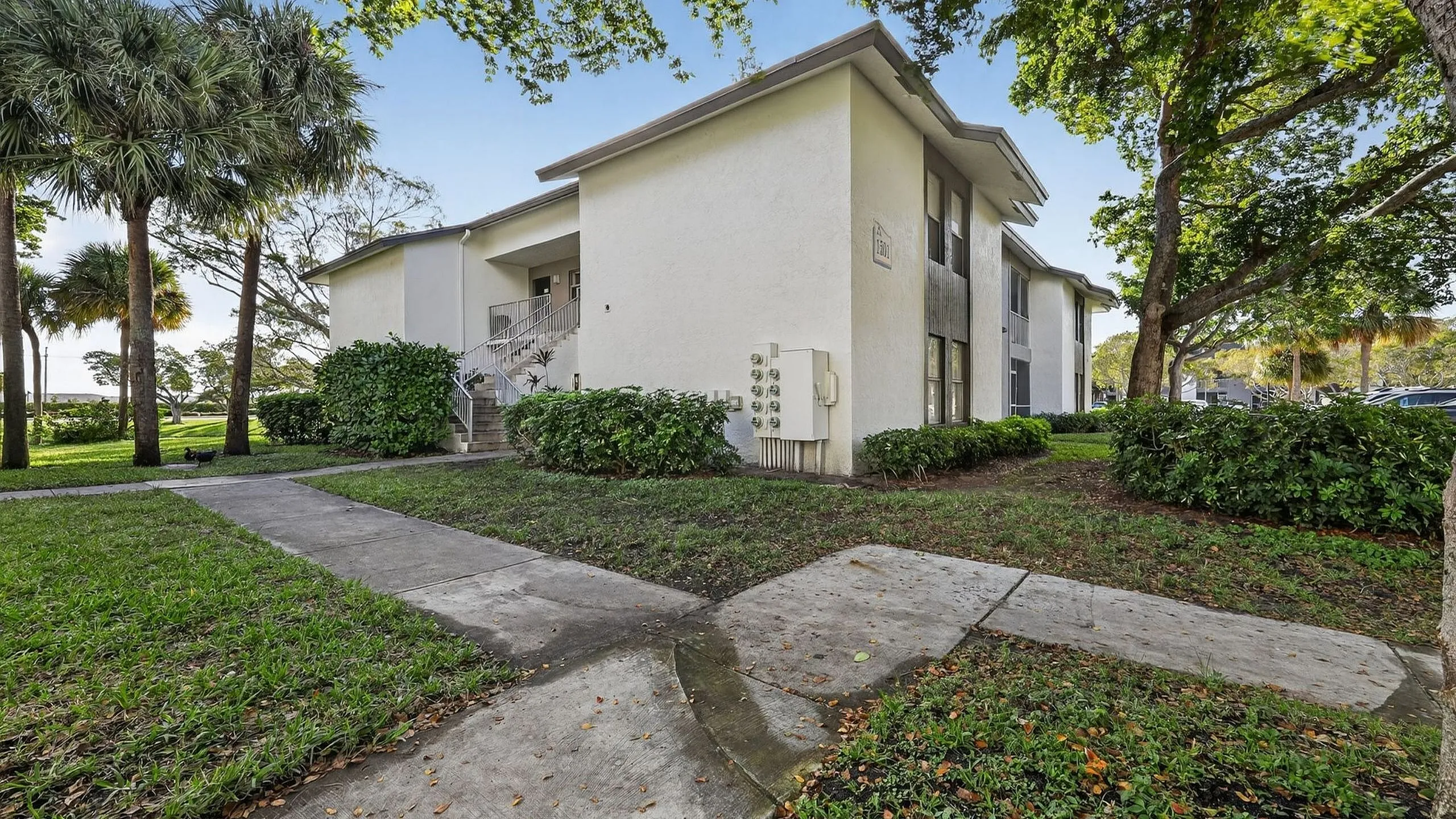 Charming residential building surrounded by lush greenery, featuring modern architecture and a peaceful walkway.