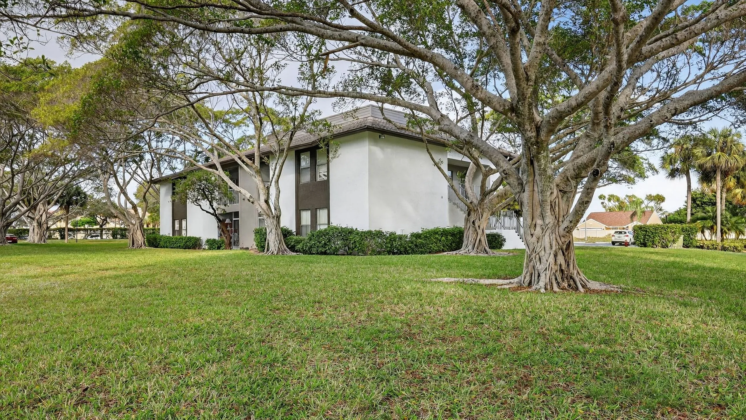Charming apartment building surrounded by lush green trees and spacious lawns, perfect for nature lovers.