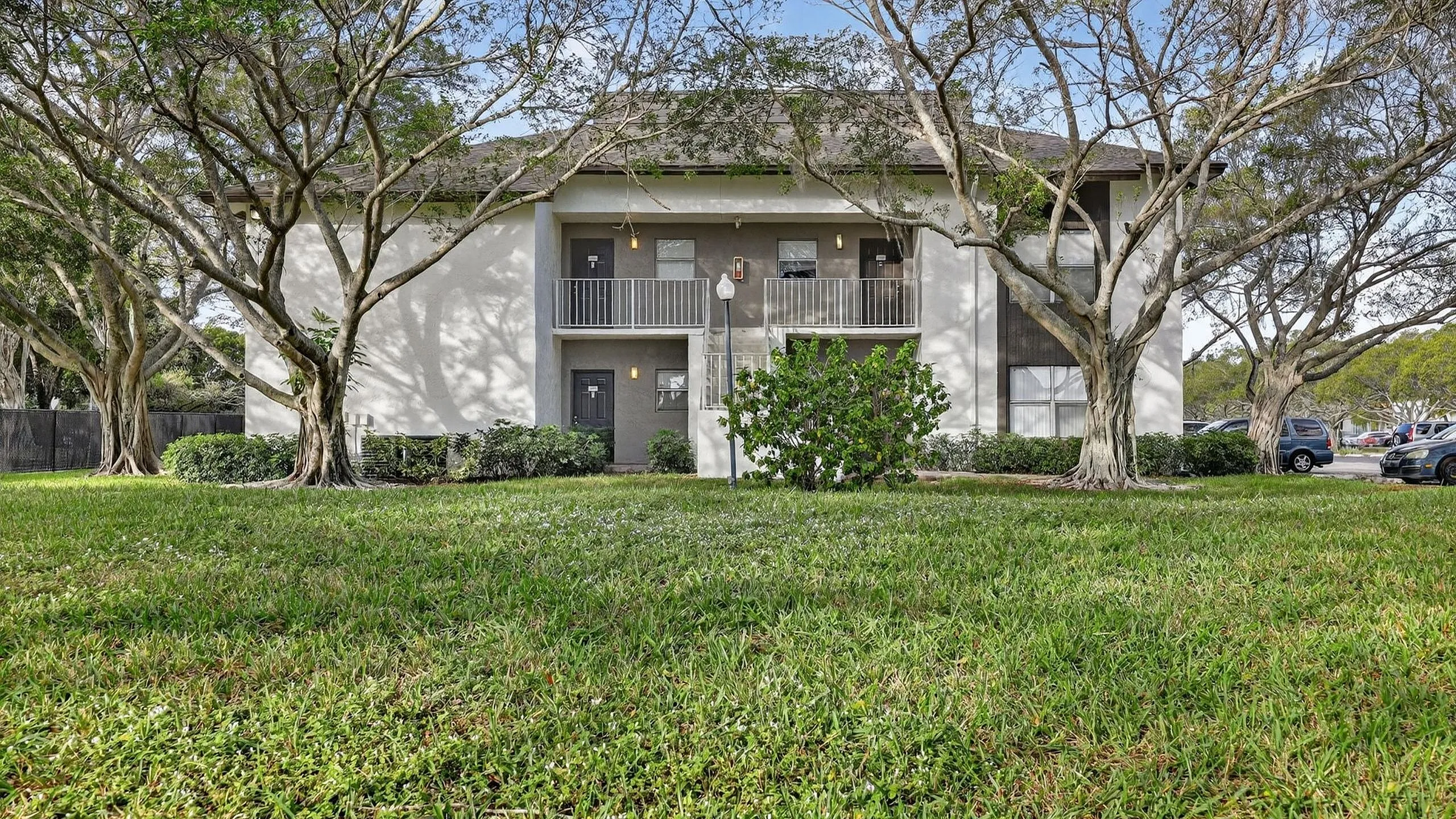 Charming apartment building facade with lush greenery and mature trees, offering a peaceful residential setting.