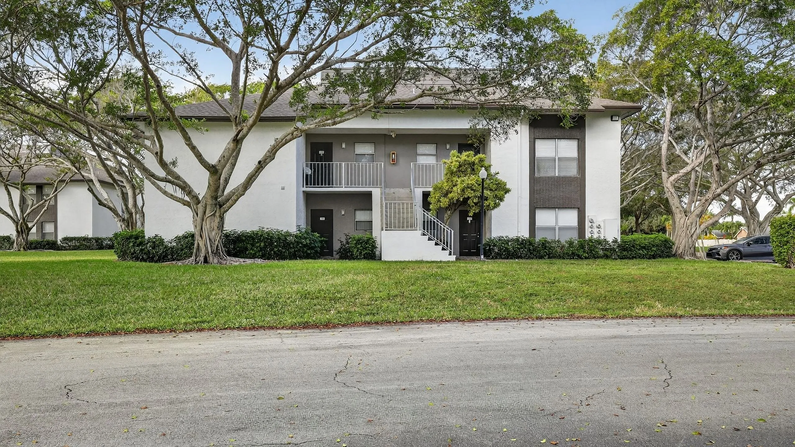 Charming apartment building surrounded by lush greenery and mature trees, offering a serene living environment.