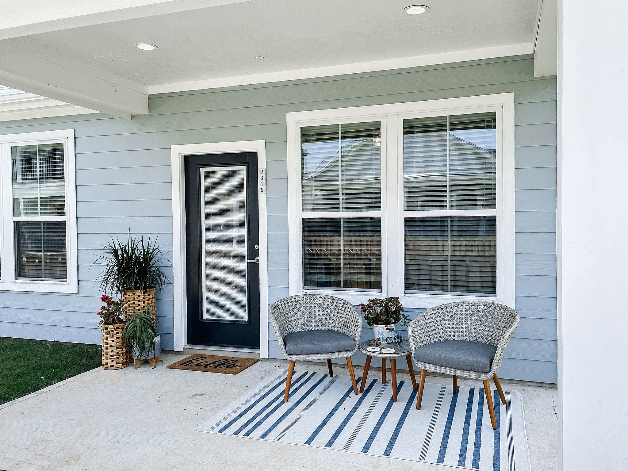 Charming front porch with comfortable wicker seating, decorative plants, and a welcoming atmosphere.