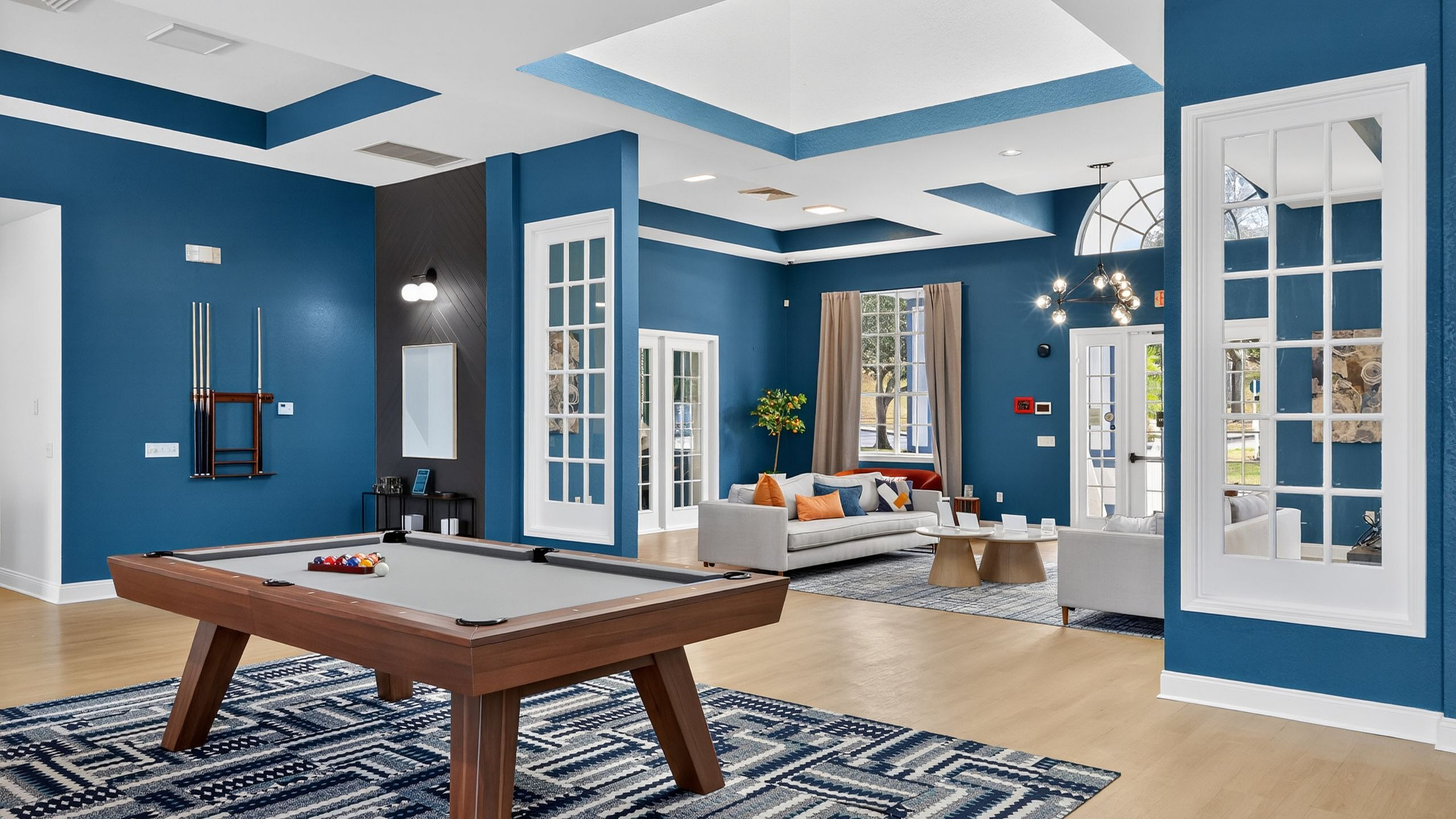 Modern recreational room with a stylish pool table, contemporary seating area, and vibrant blue accents, perfect for entertaining.
