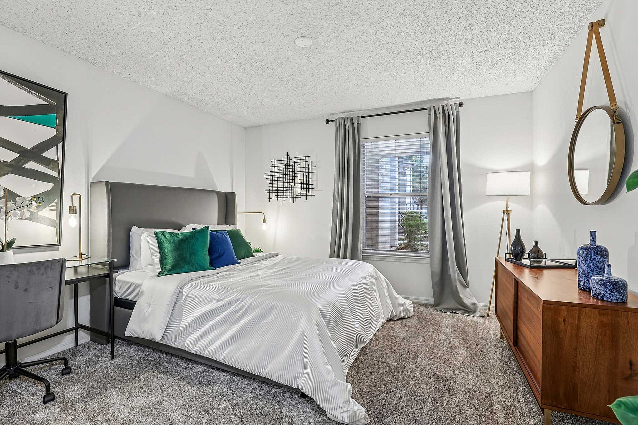 Elegant bedroom featuring a plush bed with crisp white linens, modern decor, and a serene ambiance highlighted by natural light through large windows.