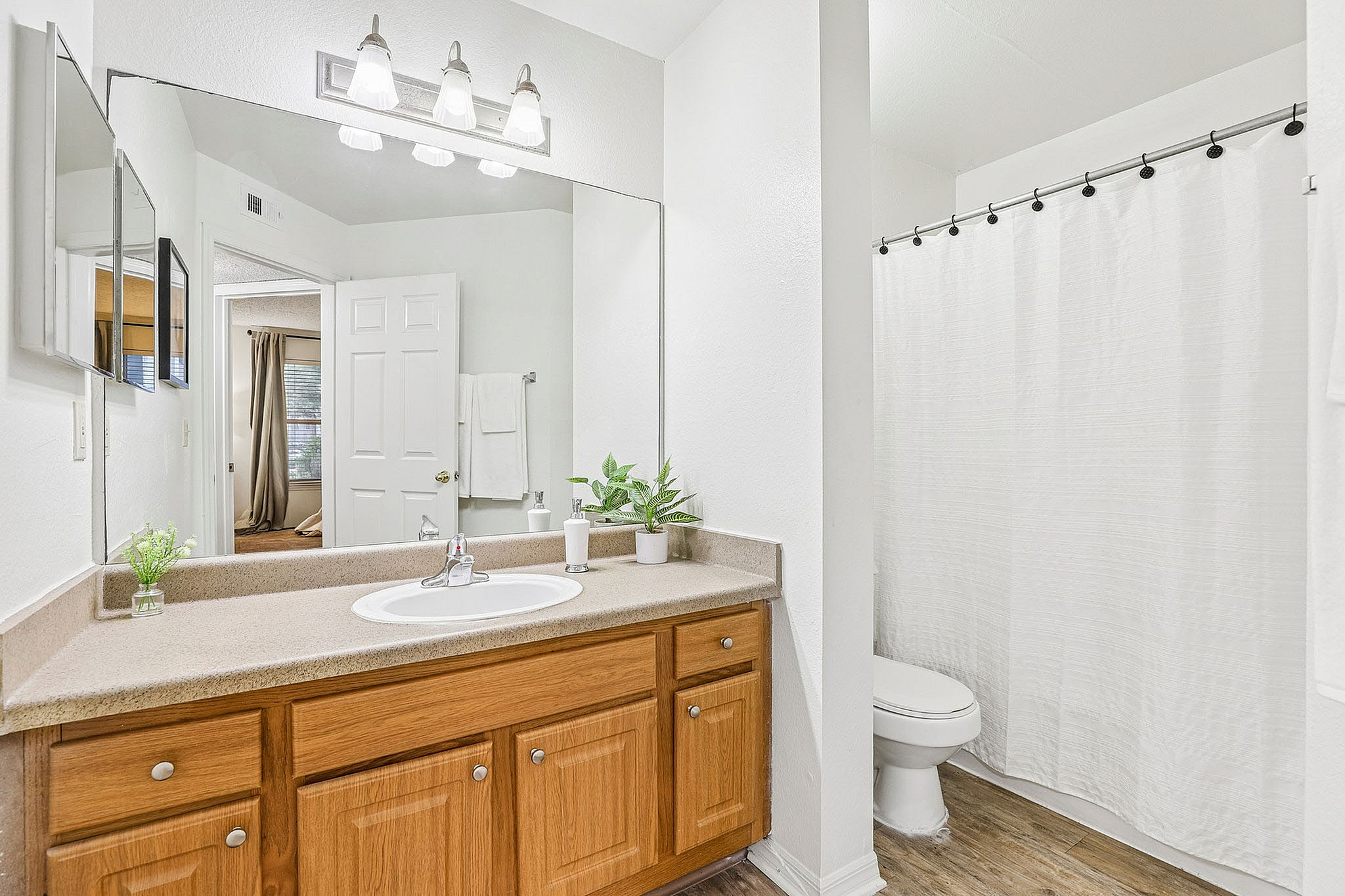Bright and inviting bathroom with modern lighting, sleek counter space, and wooden cabinetry, offering a cozy and elegant feel.
