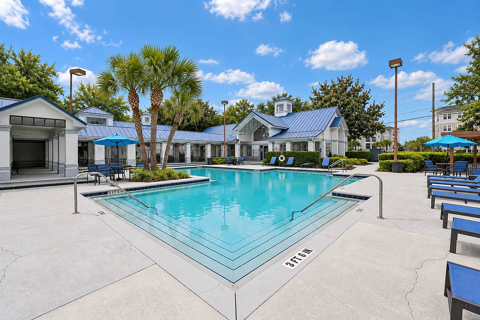Luxurious apartment complex featuring a pristine outdoor pool surrounded by palm trees and stylish seating areas, ideal for relaxation and leisure.