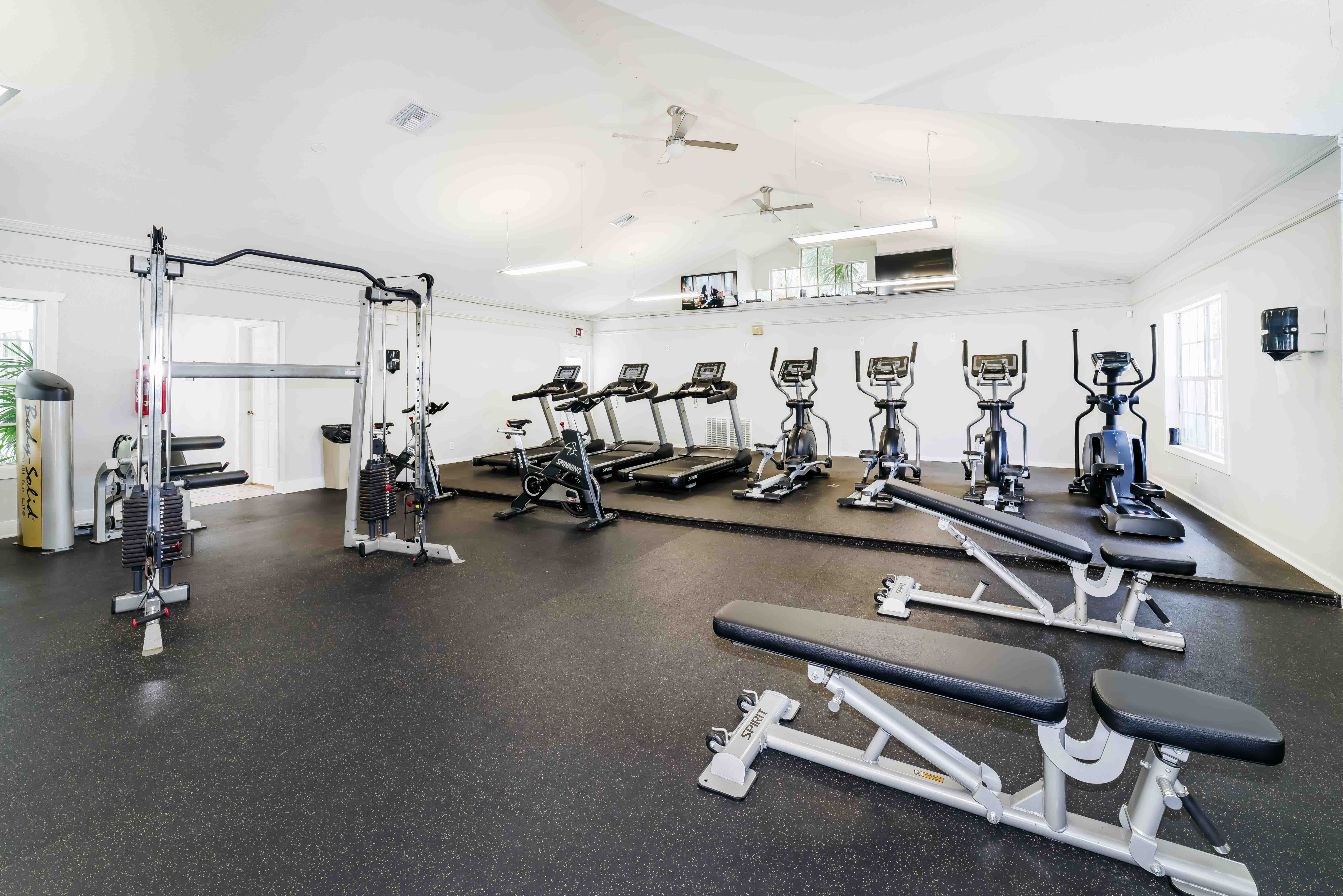 Modern fitness center featuring state-of-the-art gym equipment, treadmills, and aerobic machines in a bright, spacious room.