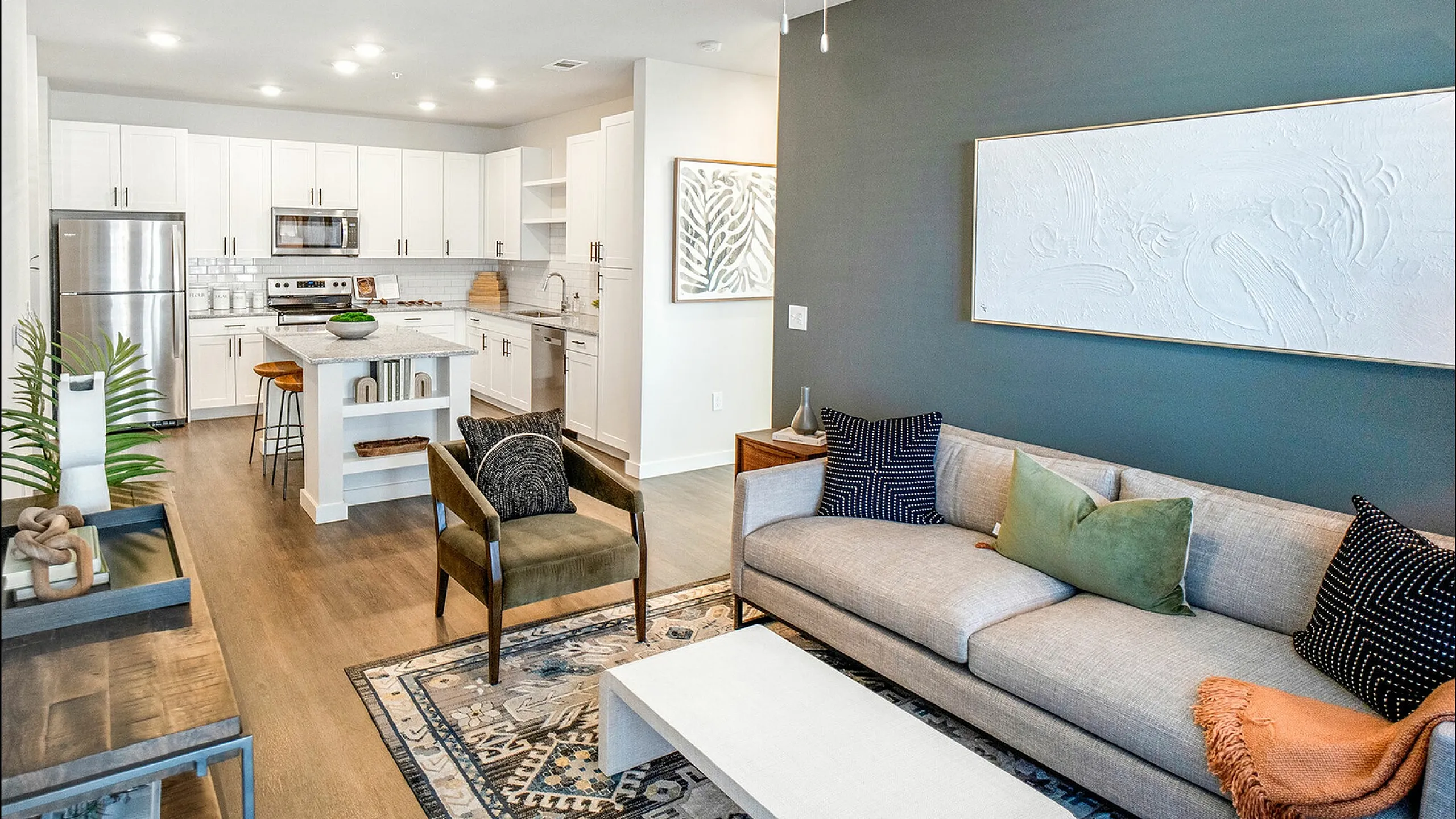 Bright modern apartment with open kitchen and living area, featuring stylish decor and wooden flooring.