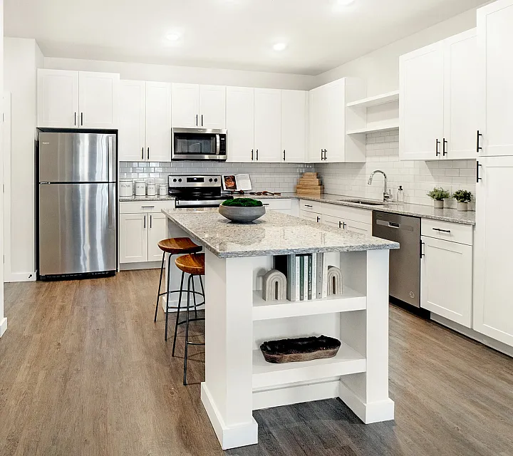 Elegant and spacious kitchen with sleek white cabinetry, stainless steel appliances, and a central island with bar stools.