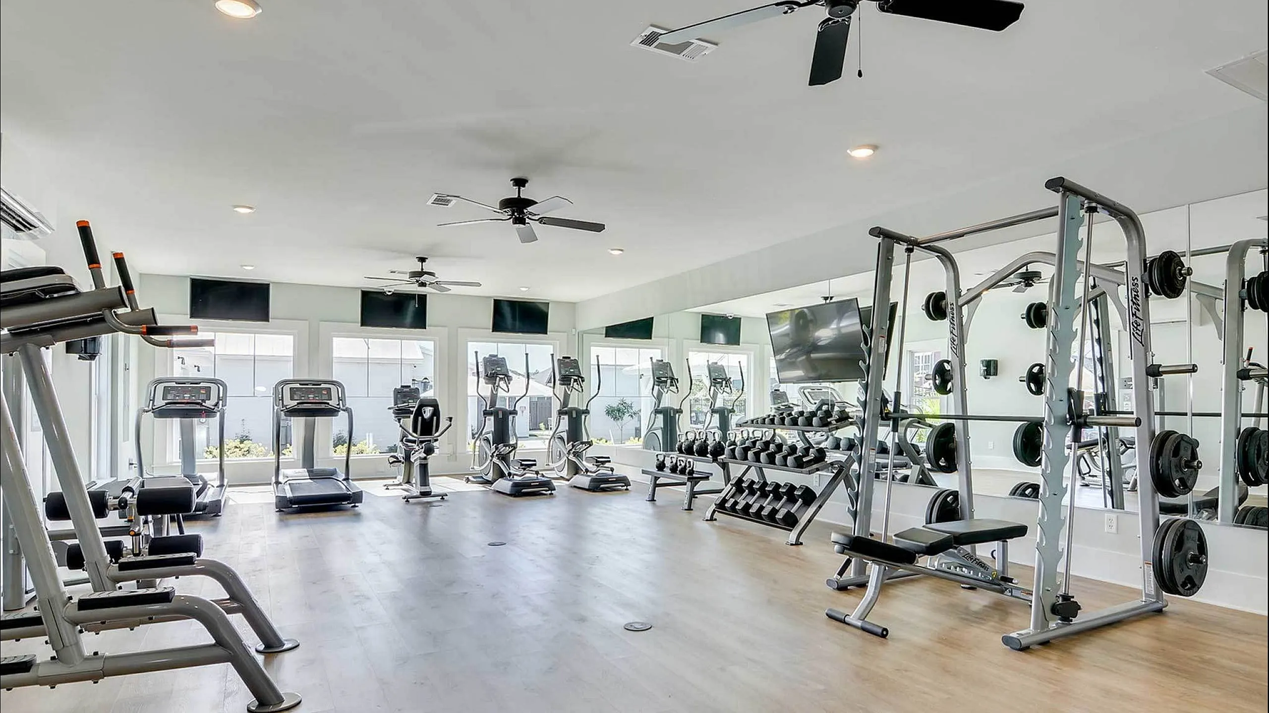 Spacious and well-lit fitness center with treadmills, weight machines, and large mirrors.