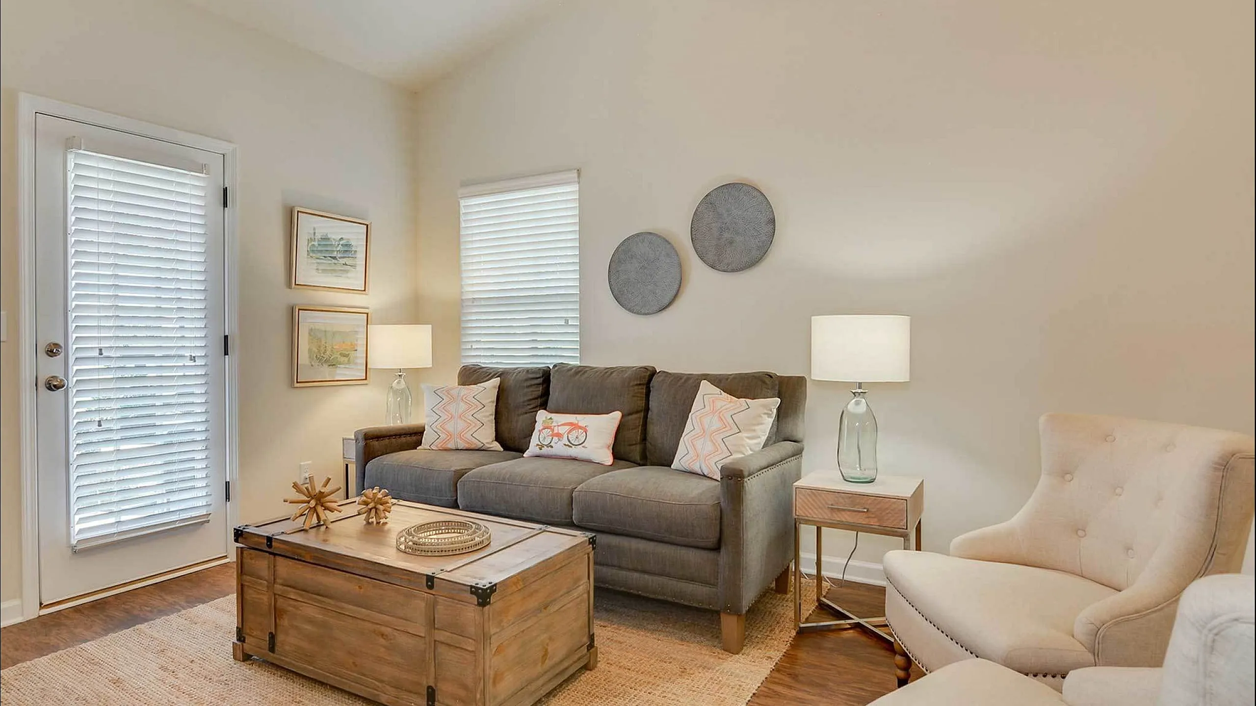 Cozy living room with modern decor, featuring a gray sofa, armchairs, and a rustic wooden coffee table.