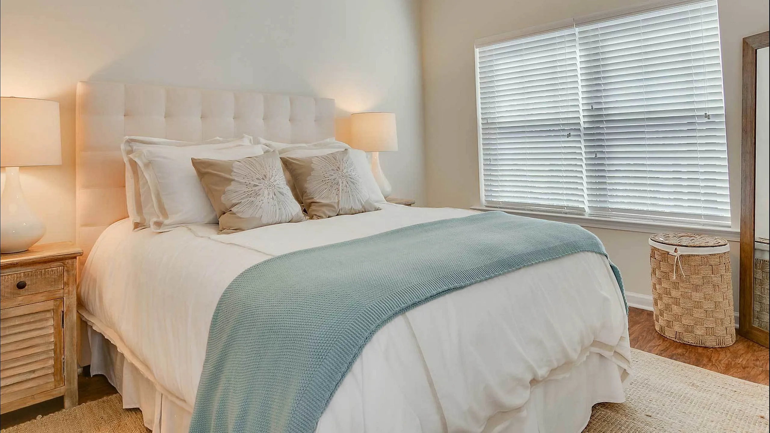 Modern bedroom with plush bed, elegant decor, and ample natural light.