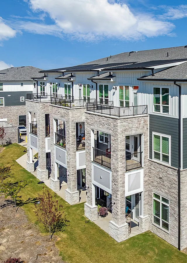 Modern apartment complex with stone and siding exterior, featuring balconies and well-maintained landscaping.