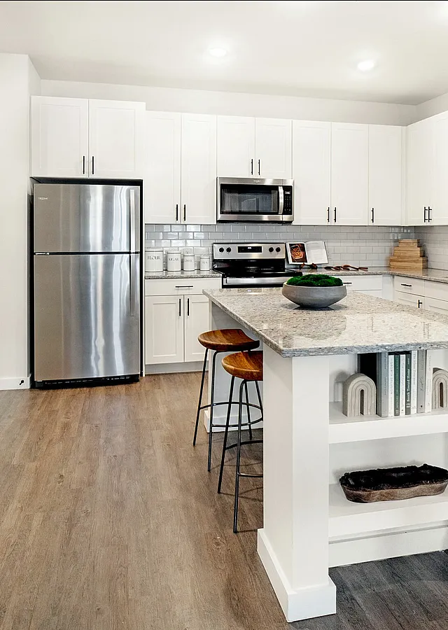 Spacious modern kitchen with white cabinetry, sleek granite countertops, and stainless steel appliances