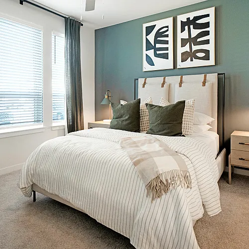 Chic modern bedroom with plush bedding, elegant artwork, and stylish nightstands.
