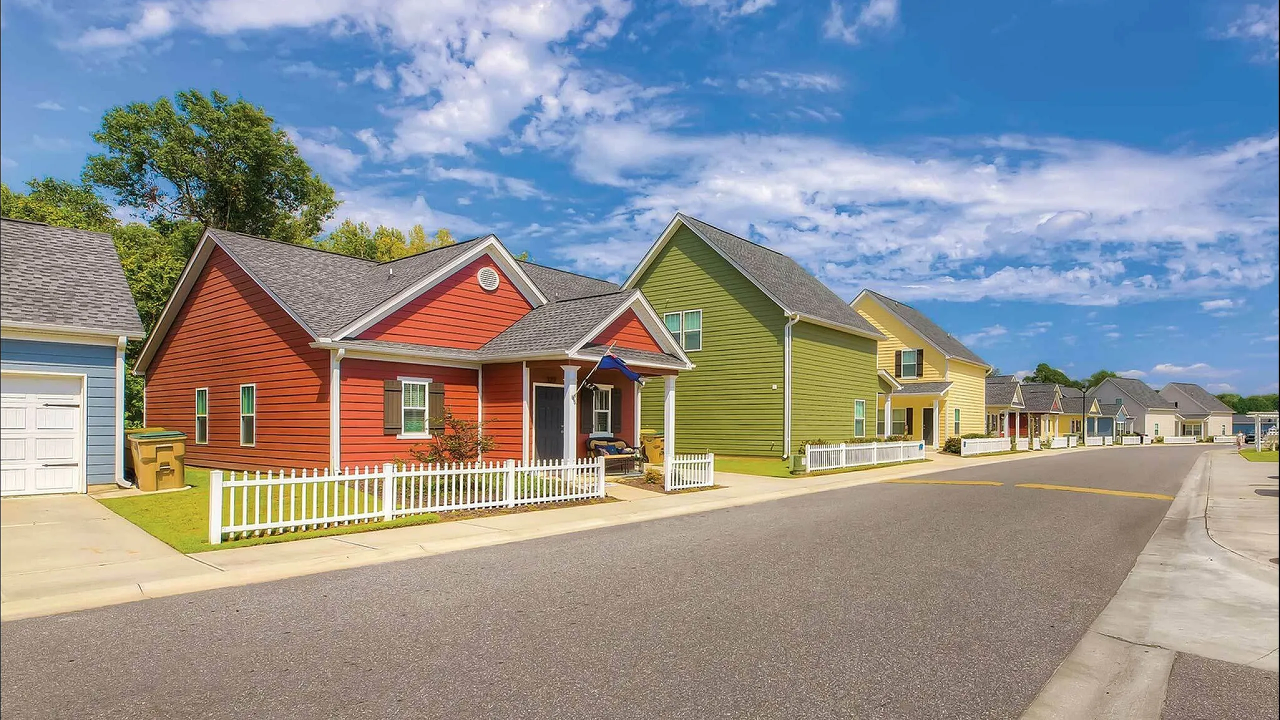 Vibrant neighborhood street with colorful houses and clear blue sky.