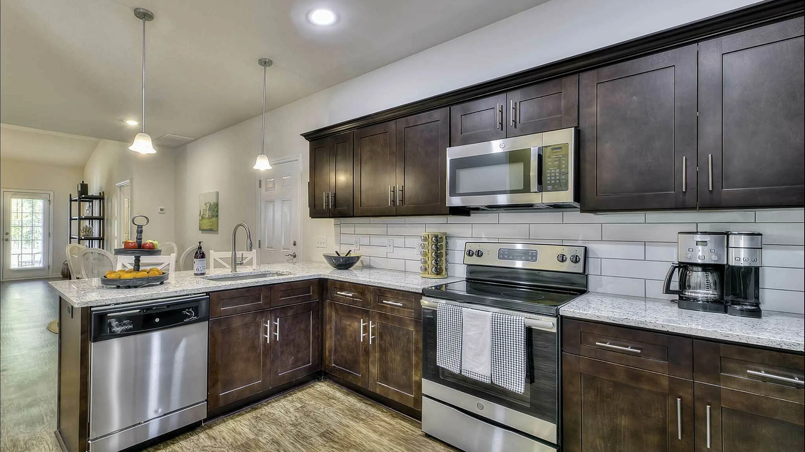 Contemporary kitchen with stainless steel appliances, dark wood cabinets, and elegant lighting