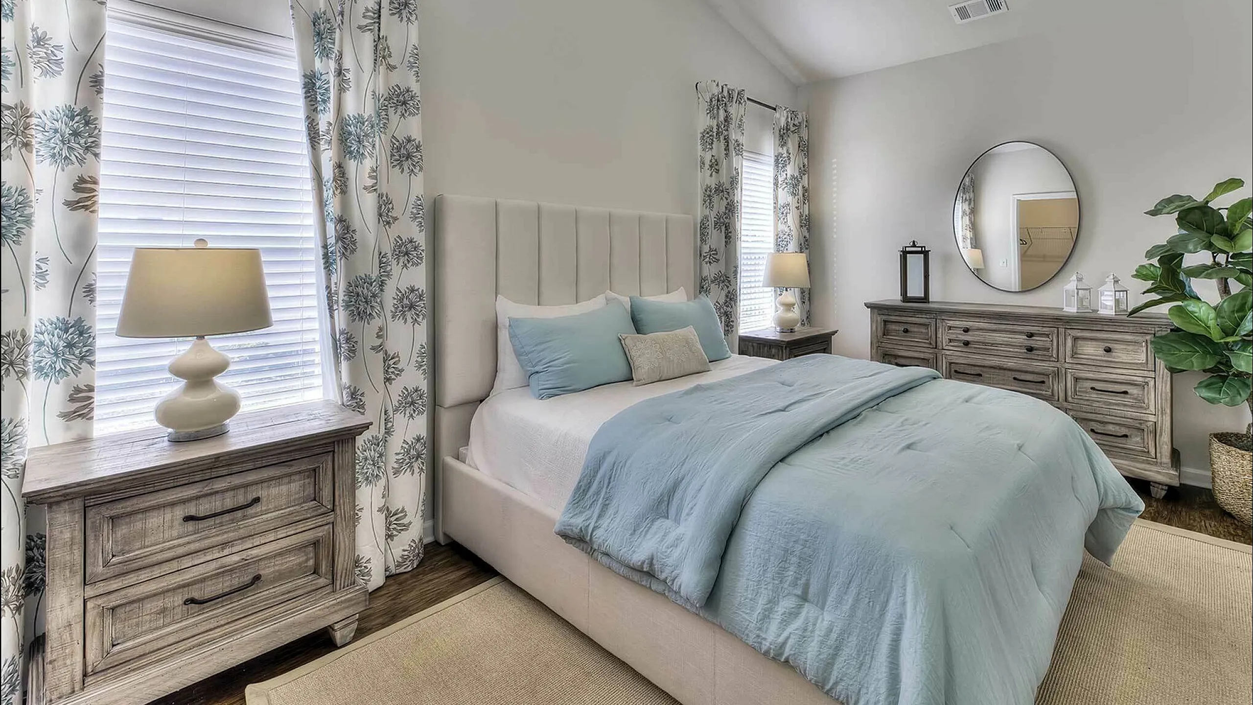 Stylish and tranquil bedroom with plush bed, elegant wooden furniture, and floral curtains.