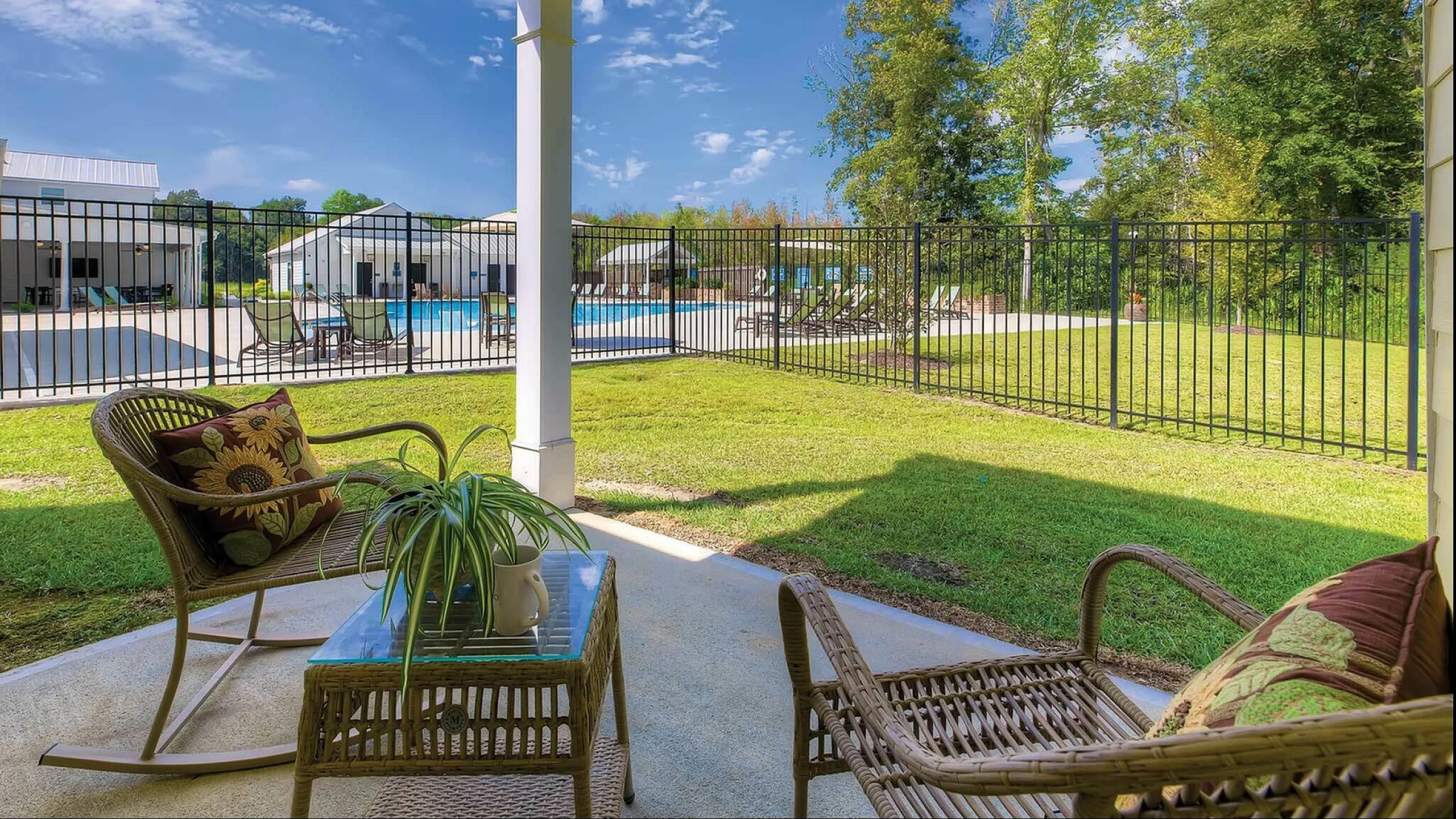 Inviting patio with wicker furniture and lush view of poolside area