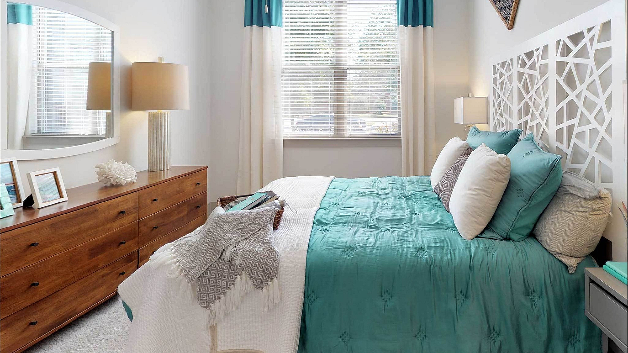 Bright and inviting bedroom with turquoise bedding, wooden dresser, and elegant decor accents.