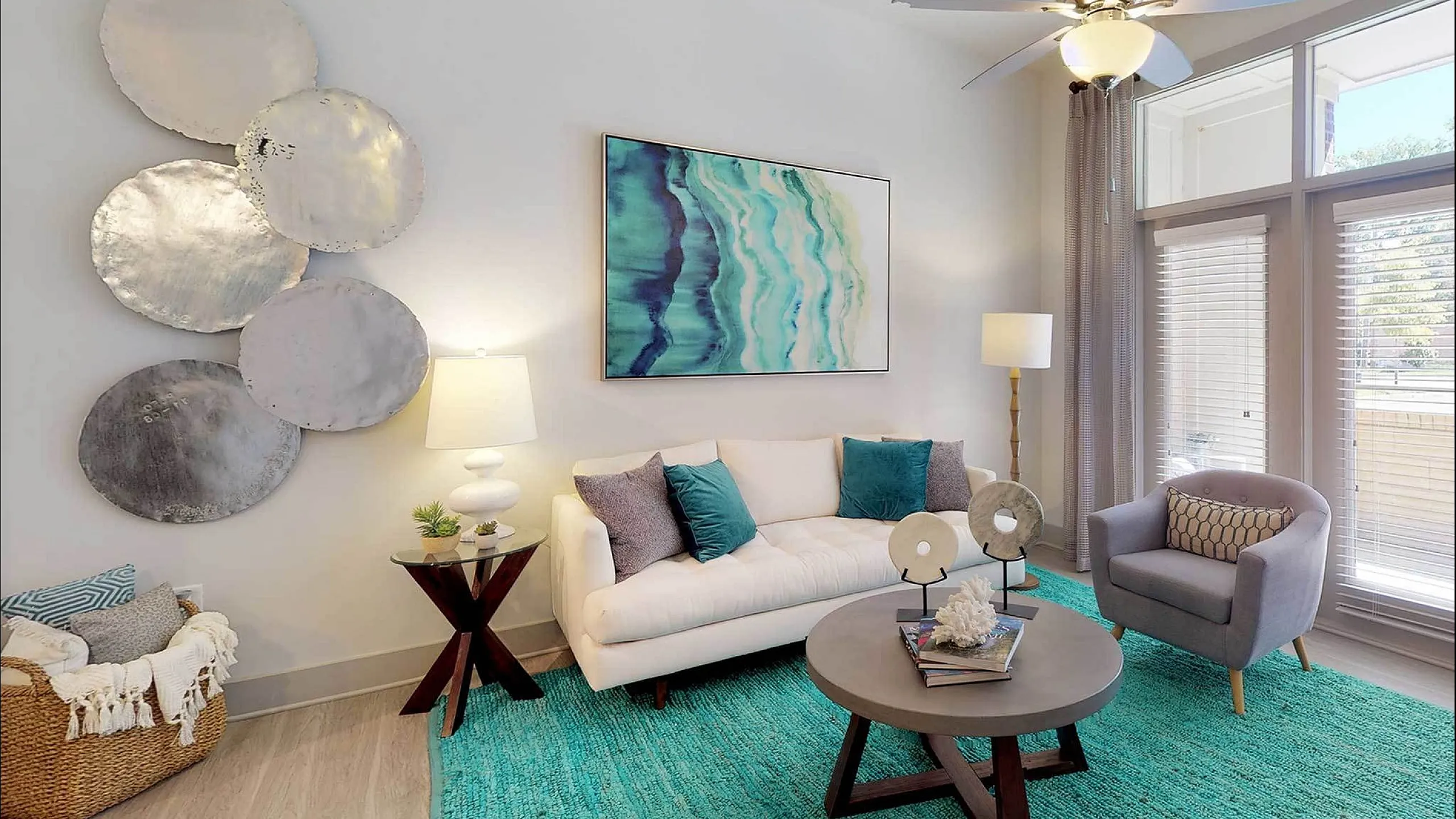 Bright living room with modern decor, vibrant teal rug, and natural light