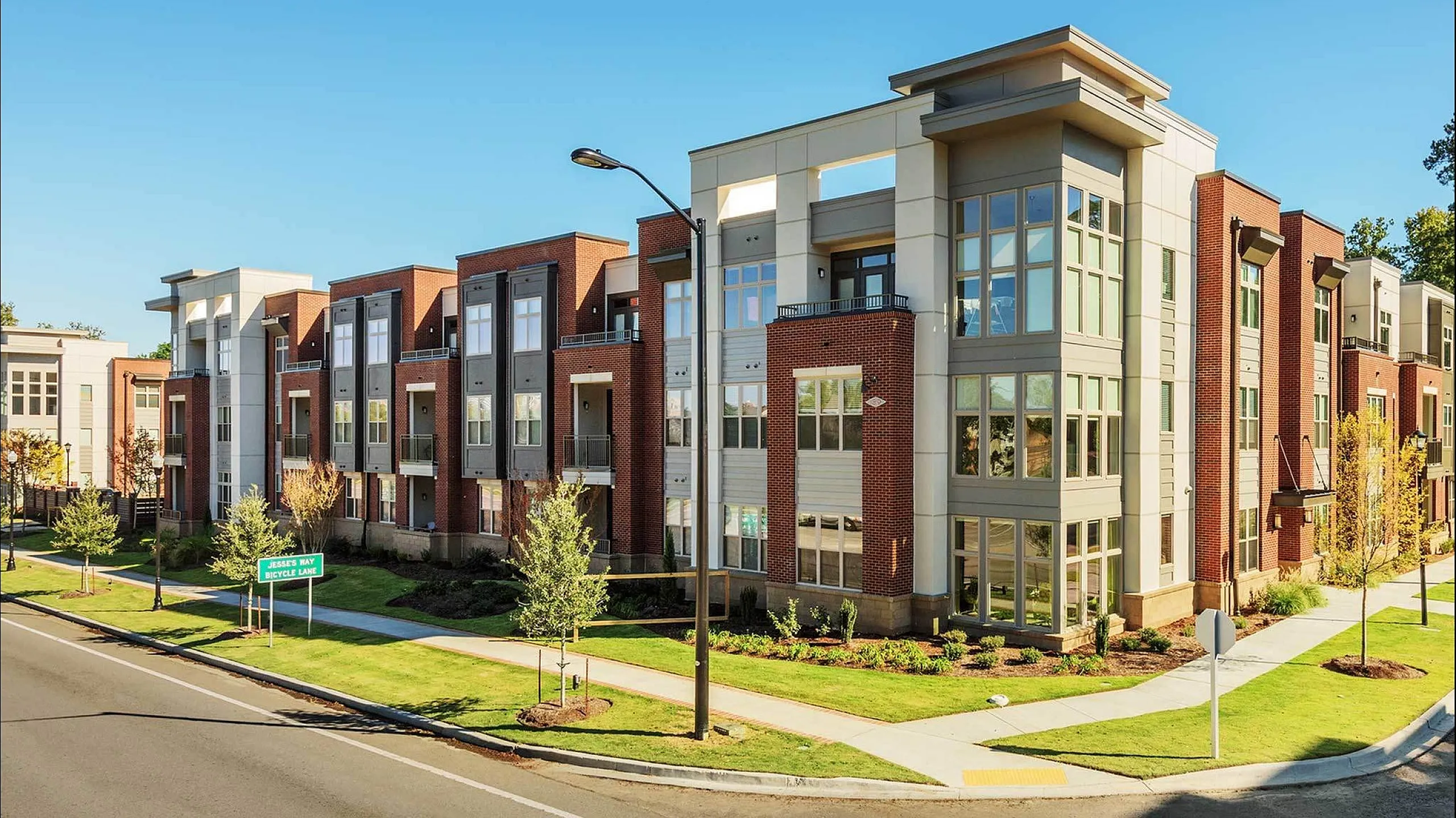 Modern apartment complex with large windows and brick facade on a sunny day