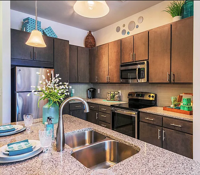 Modern kitchen with stainless steel appliances, granite countertops, and elegant pendant lighting.