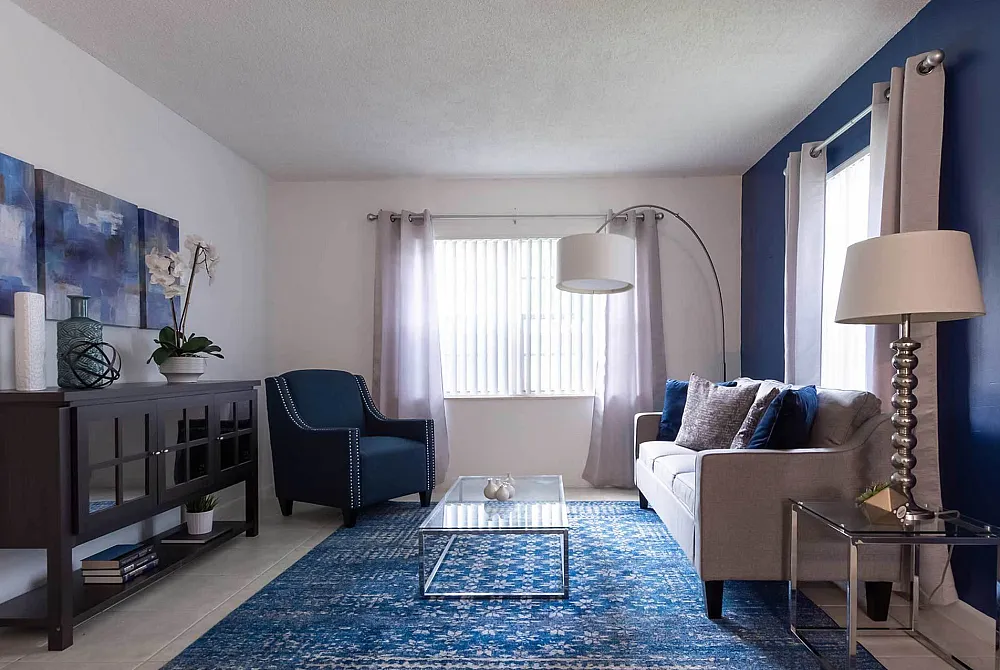 Stylish living room with blue and gray decor, featuring a cozy sofa, elegant armchair, and chic glass coffee table.