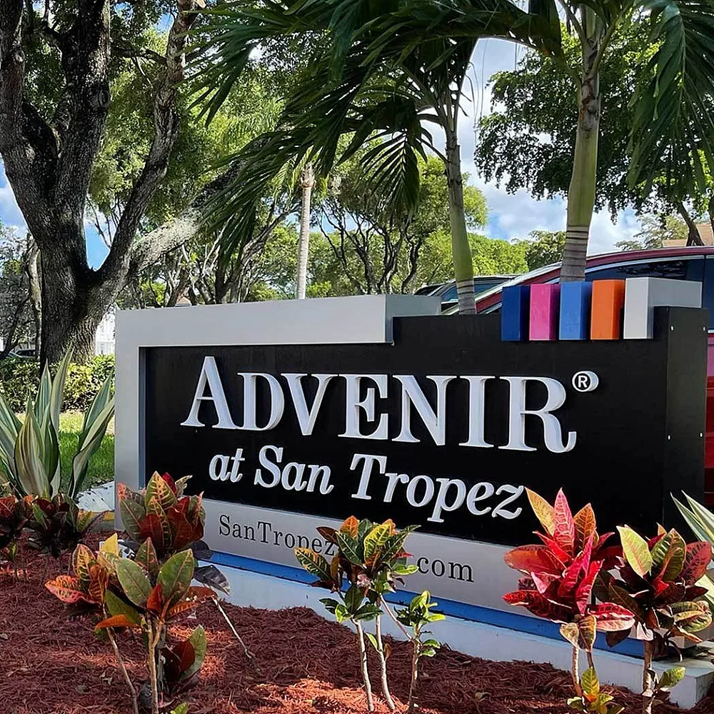 Vibrant entrance to Advenir at San Tropez with tropical landscaping and elegant signage.