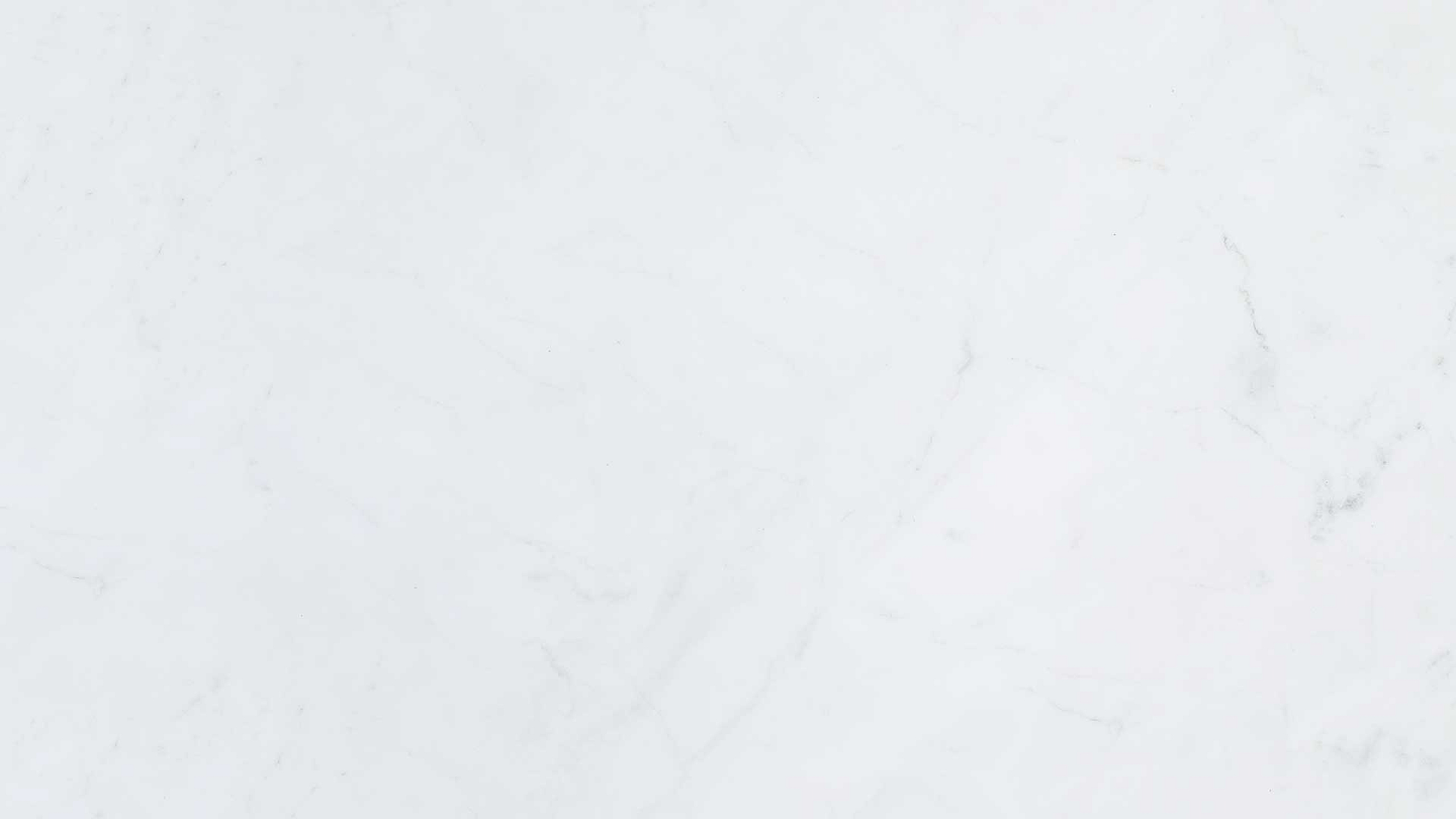 A close-up of a pristine white marble surface with subtle gray veining.