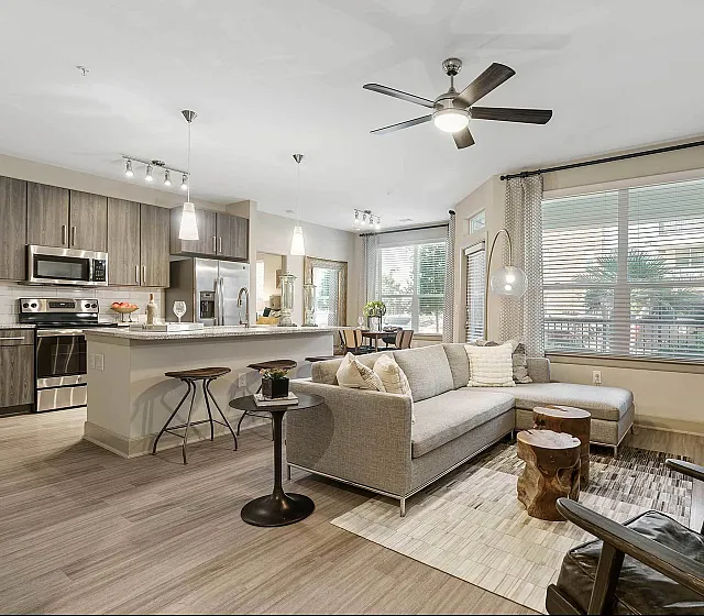 Contemporary open-plan apartment living room with sleek kitchen, modern appliances and stylish decor.