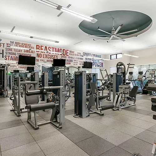 Spacious and well-equipped gym with motivational wall art and fitness machines in a modern apartment complex.