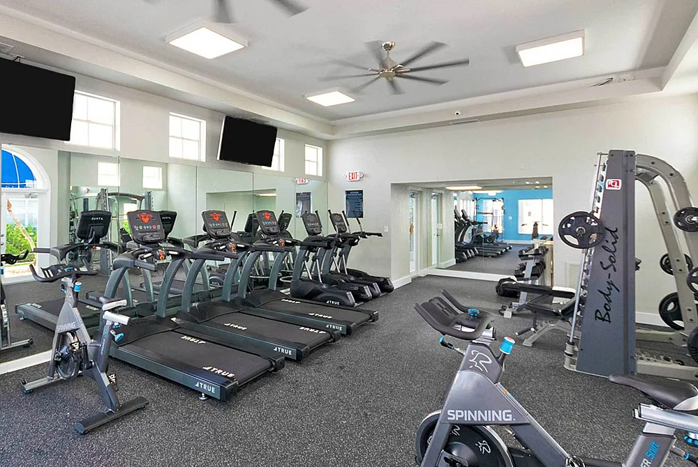 Modern fitness center with treadmills, stationary bikes, and weight machine in bright, airy space
