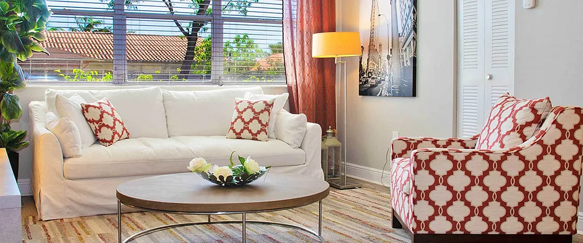 Bright and stylish living room with white sofa, patterned armchair, and large window views