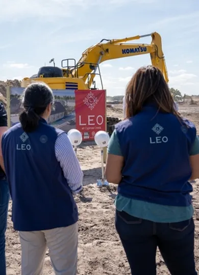 Team members at LEO project site, featuring construction equipment and project banner.