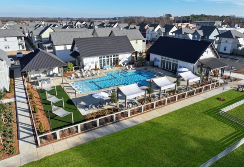 Aerial view of a modern community pool area with elegant lounge spaces, surrounded by contemporary homes.