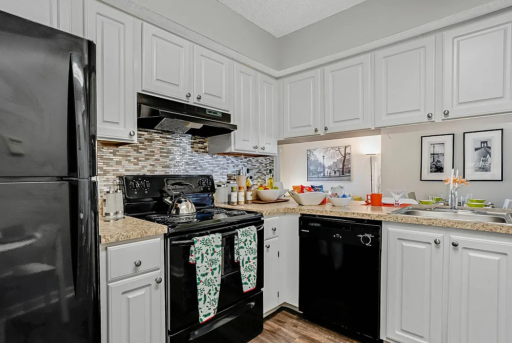 Charming kitchen with elegant white cabinetry, sleek black appliances, and stylish mosaic backsplash, creating a welcoming atmosphere.