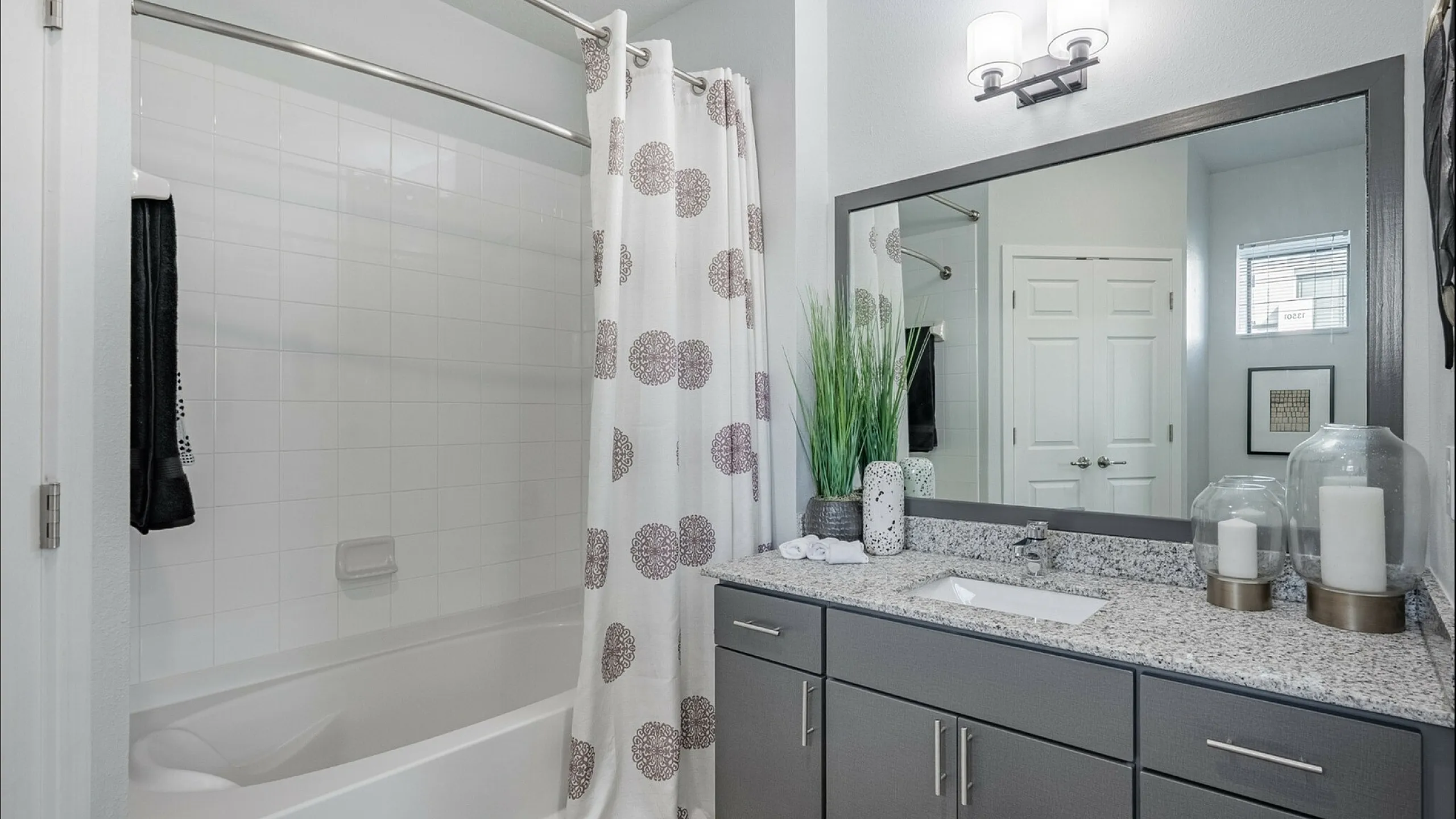 Elegant bathroom featuring a spacious vanity with modern fixtures and a stylish shower curtain, enhanced by natural lighting.