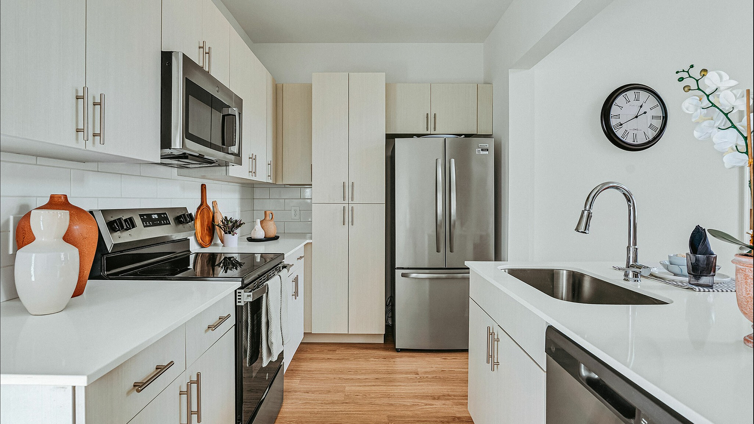 Modern kitchen with sleek white cabinets, stainless steel appliances, and elegant d&eacute;cor elements enhancing a spacious feel.