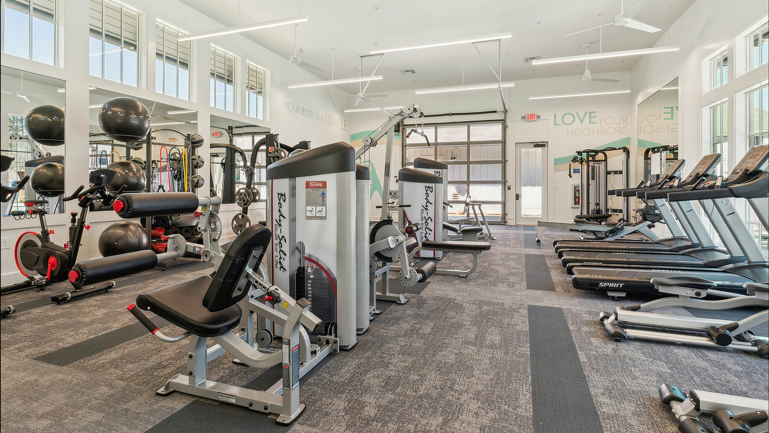 Modern fitness center equipped with state-of-the-art cardio and strength training equipment, featuring large windows for natural light and a motivational ambiance.