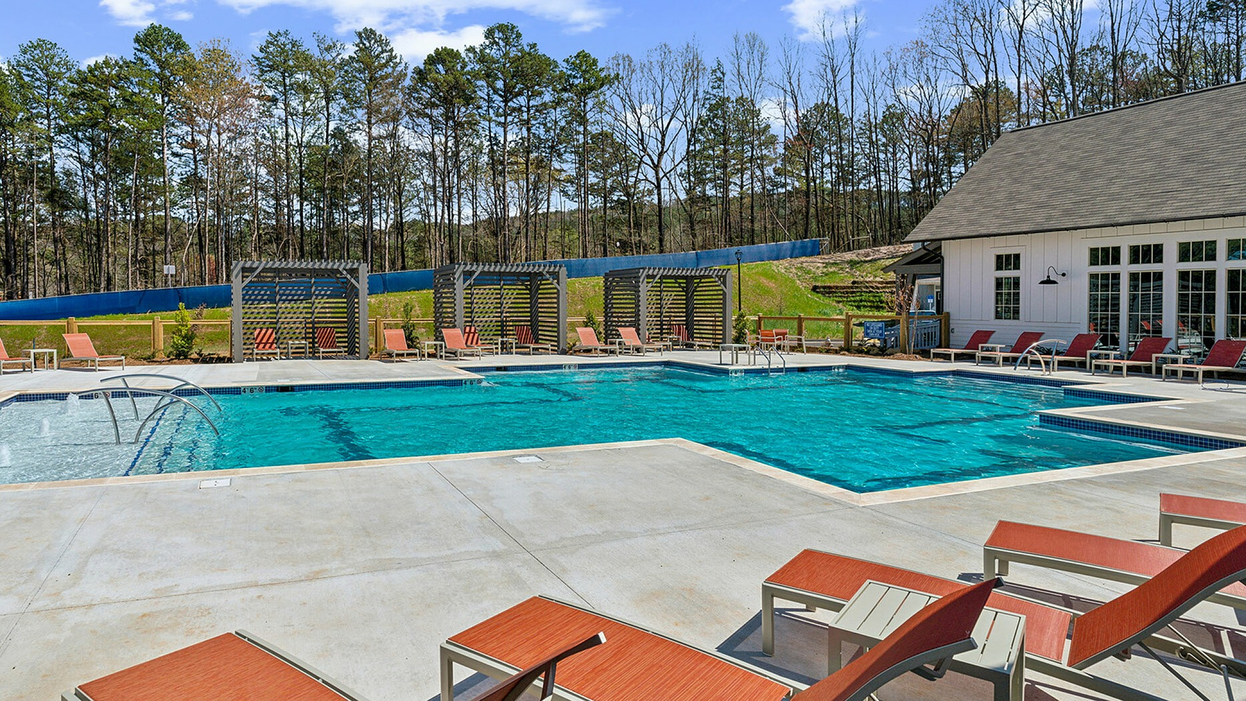 Inviting outdoor pool area with stylish lounge chairs and scenic woodland backdrop, perfect for relaxation and leisure.