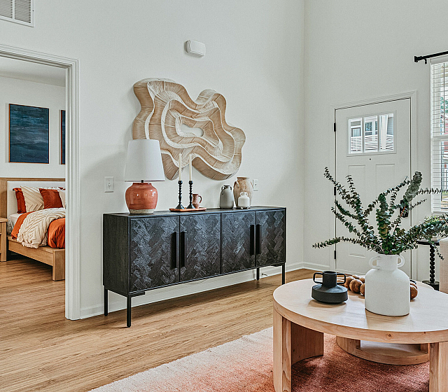 Chic modern apartment with elegant decor, showcasing a cozy living area, stylish wooden accents, vibrant orange curtains, and natural light streaming through large windows.