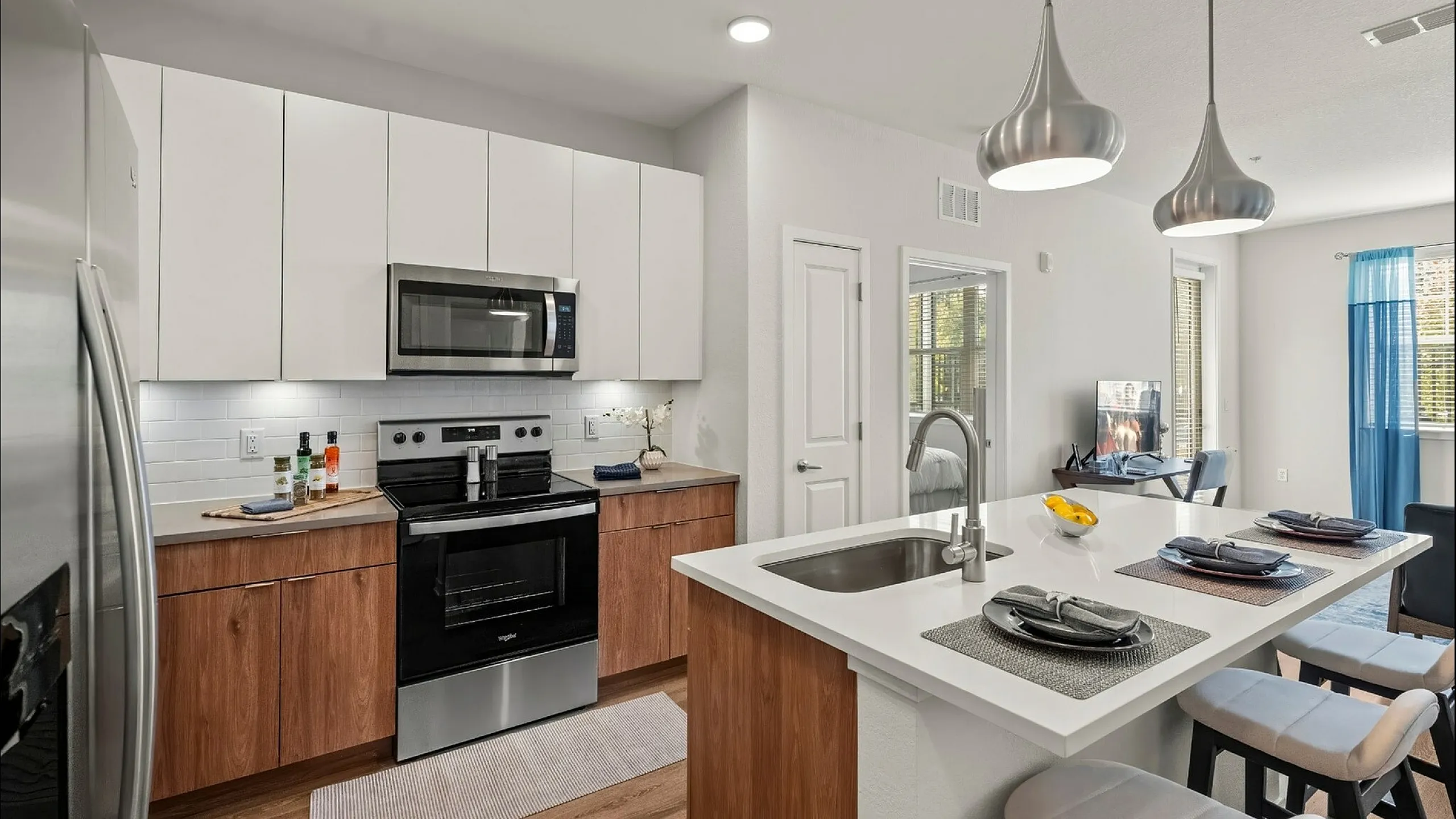 Modern open-concept kitchen with sleek countertops, stainless steel appliances, and chic pendant lighting, blending seamlessly into a bright living space.