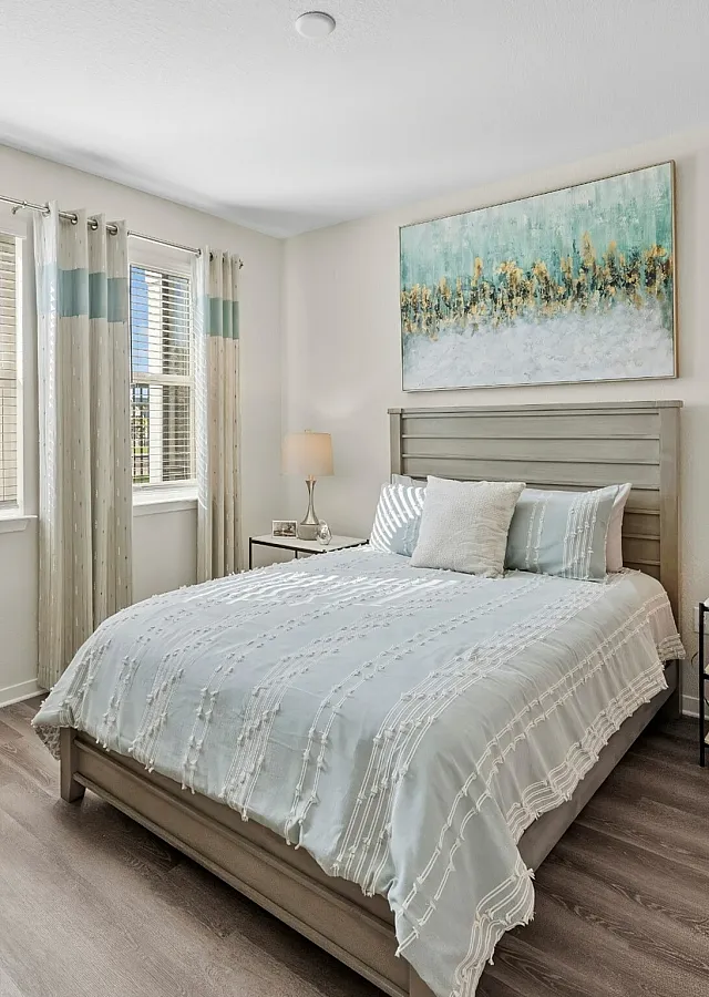 Inviting bedroom with elegant decor, featuring a comfortable bed, stylish artwork, and natural light streaming through large windows.
