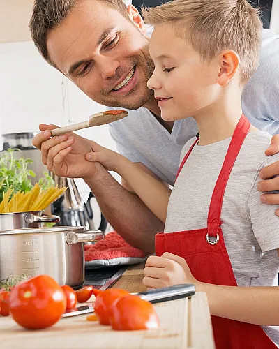 Bright kitchen scene with a joyful father and child cooking together, surrounded by fresh ingredients and modern cookware.