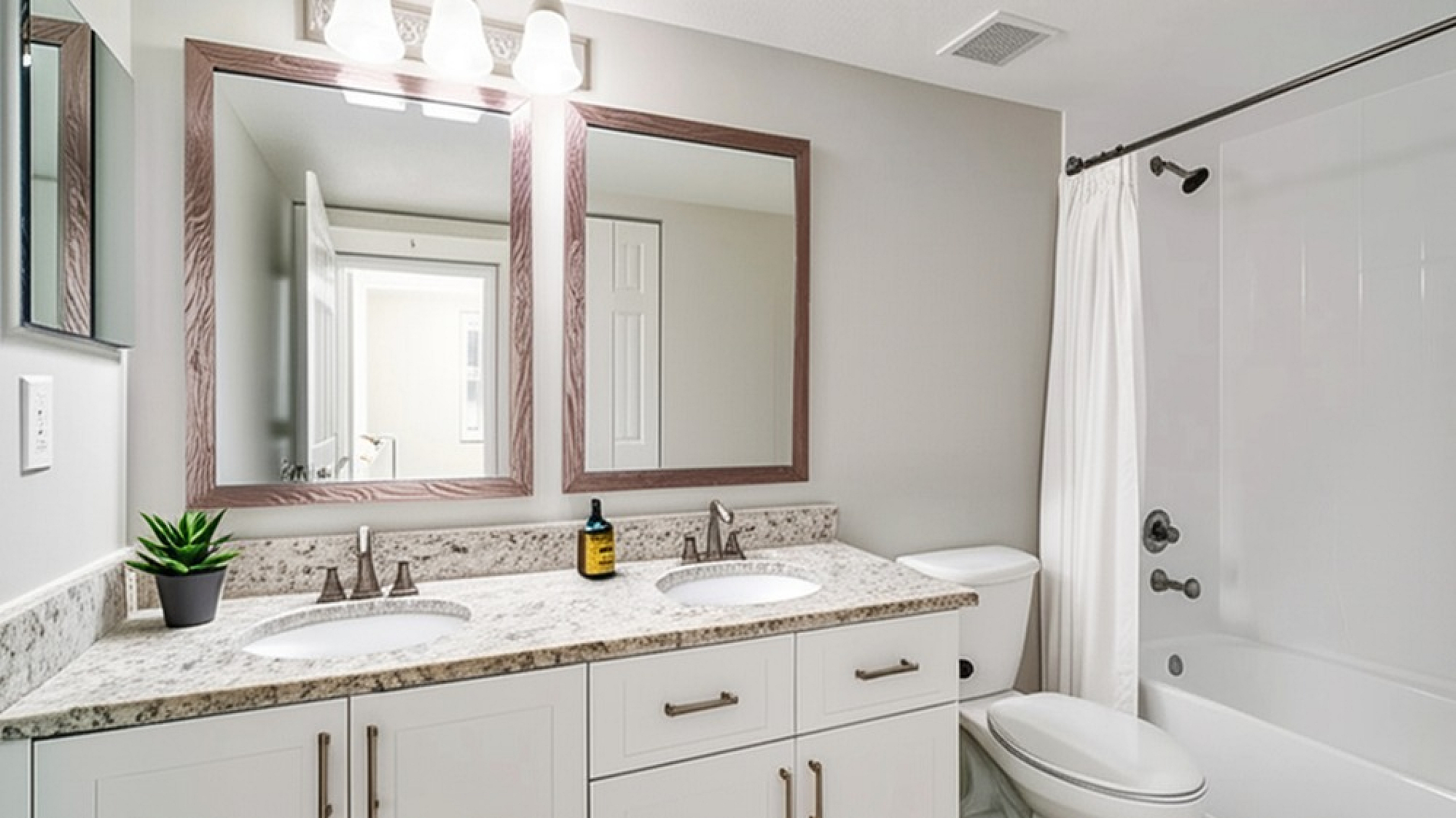 Elegant bathroom featuring dual sinks, stylish mirrors, granite countertops, and a modern bathtub.