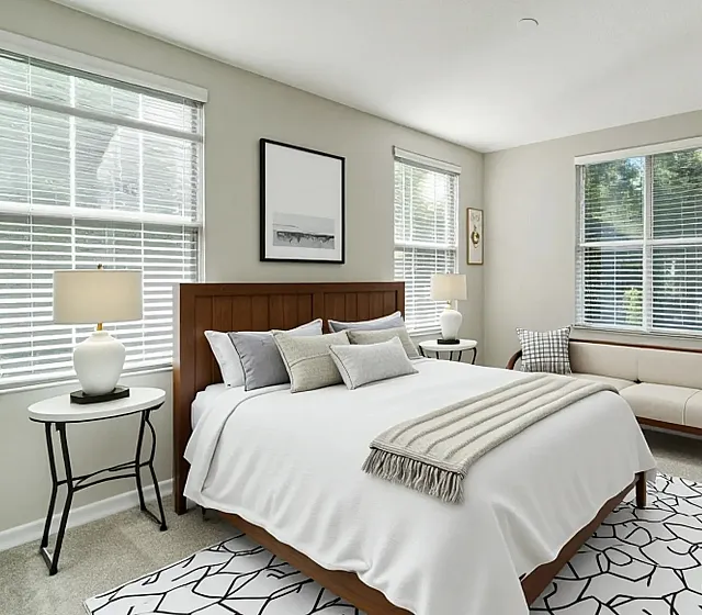 Elegant bedroom with stylish decor, featuring a cozy bed, chic side tables, modern art, and large windows for natural light.